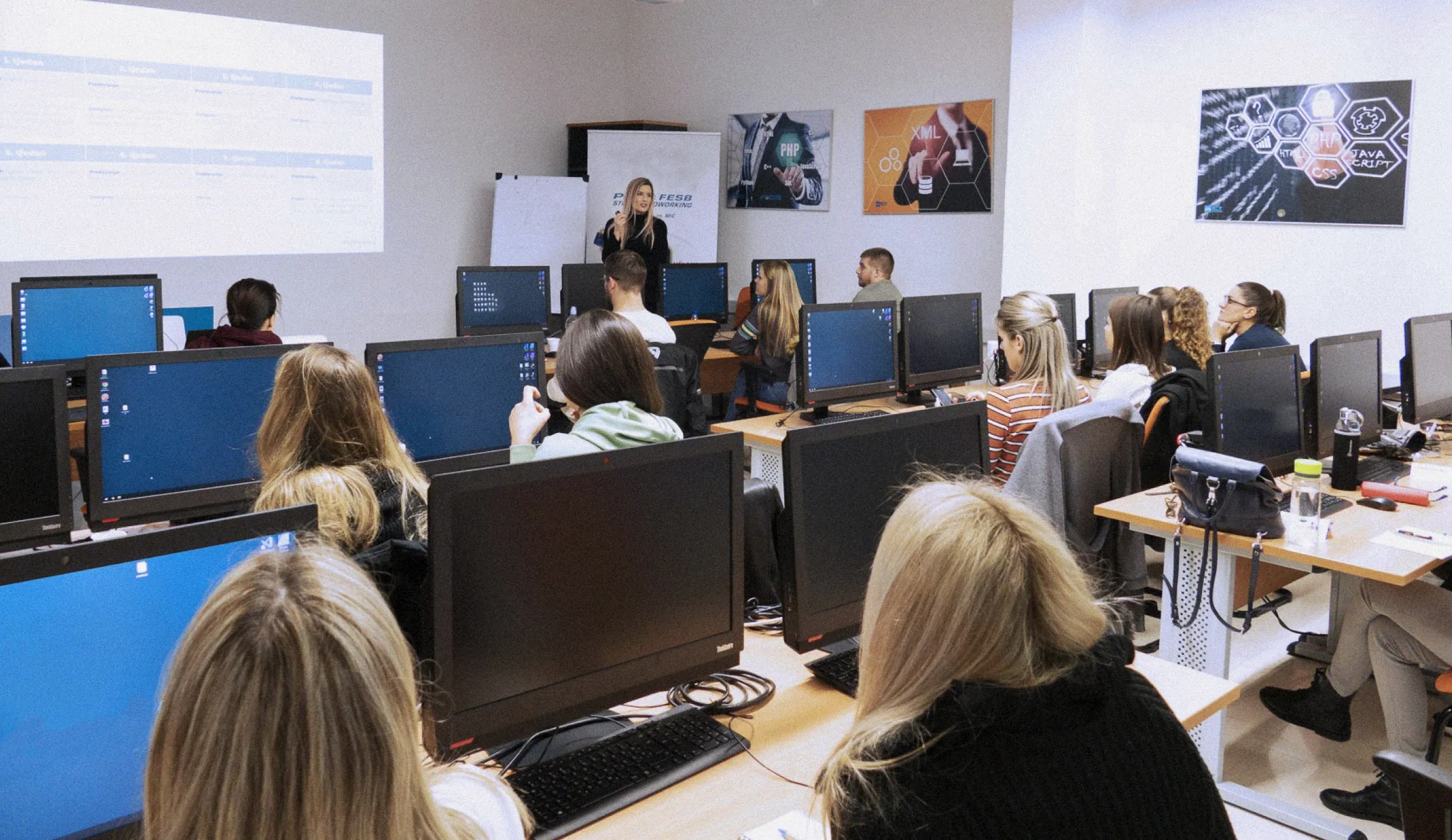 Nikolina teaching a full computer lab of students.