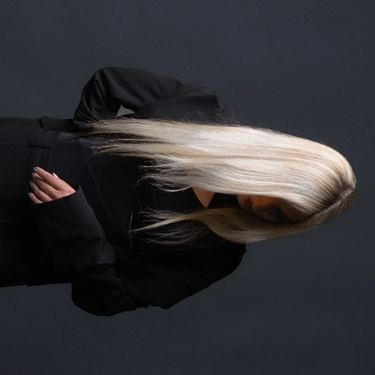 Nikolina in a black coat, hair swept across her face