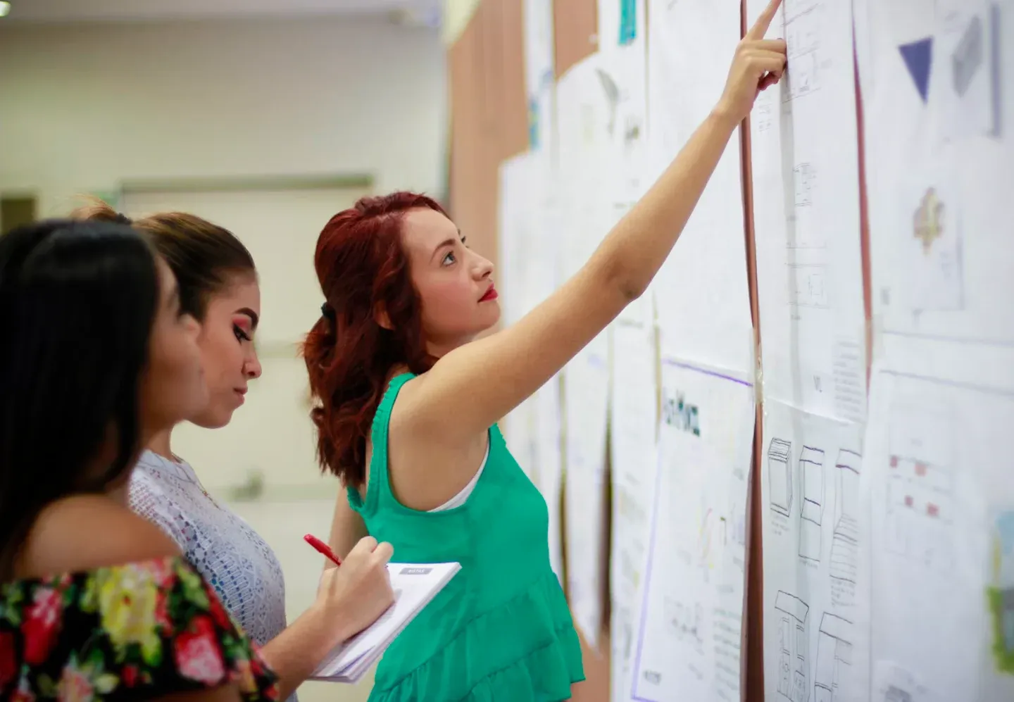 Two designers mapping a user flow across printed screens on a wall